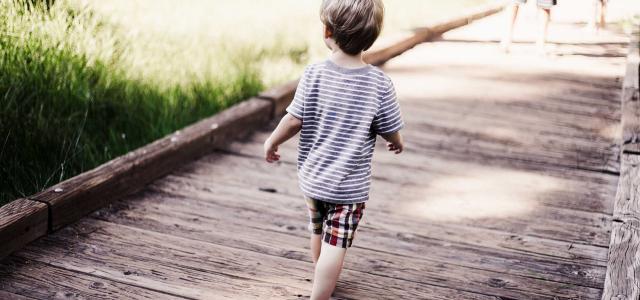 Boy running on wooden bridge.